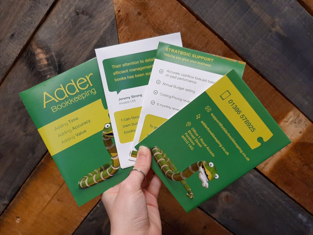 Adder Bookkeeping leaflets held against a wooden background