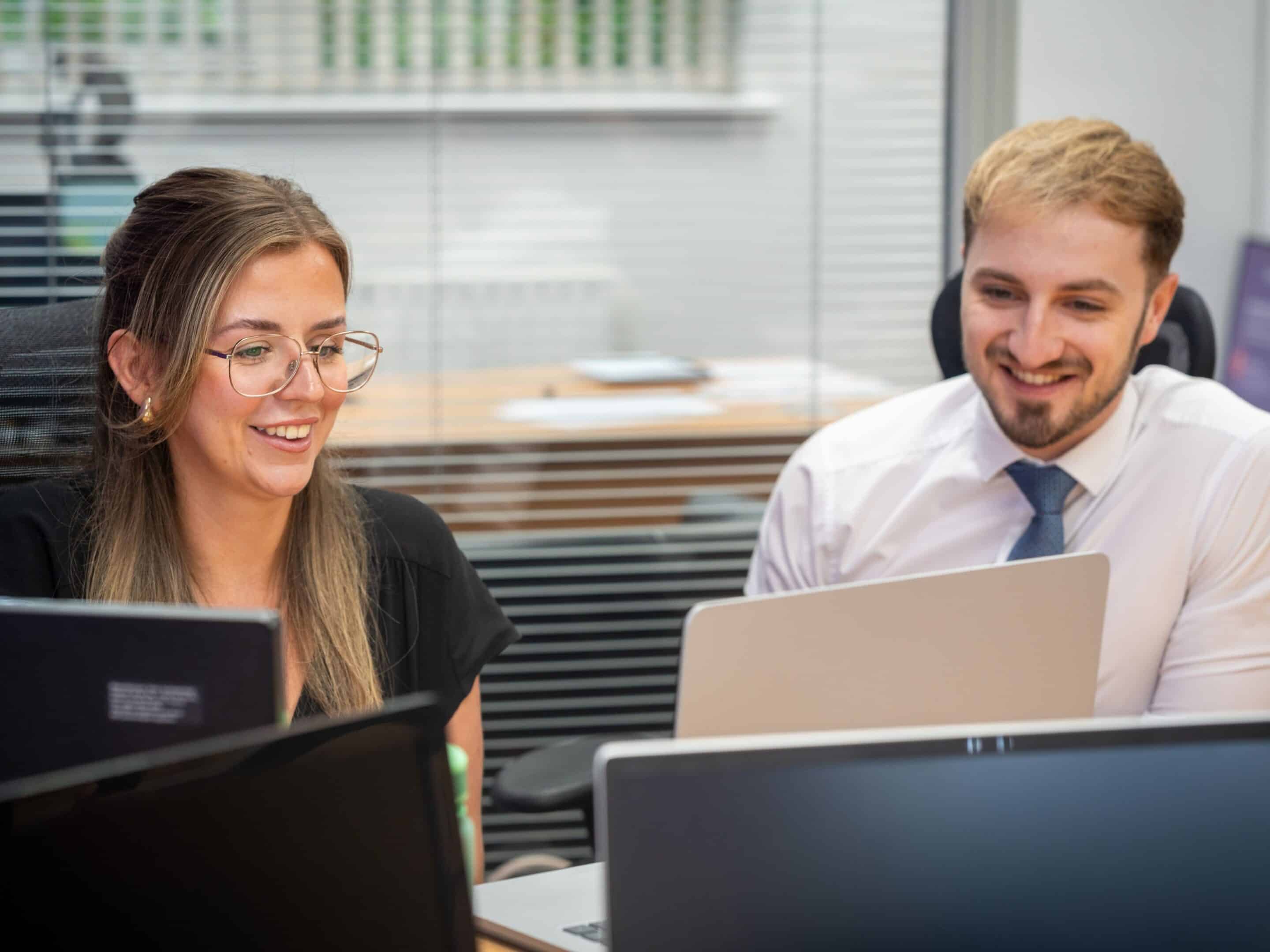 2 people looking at computer screens in an office