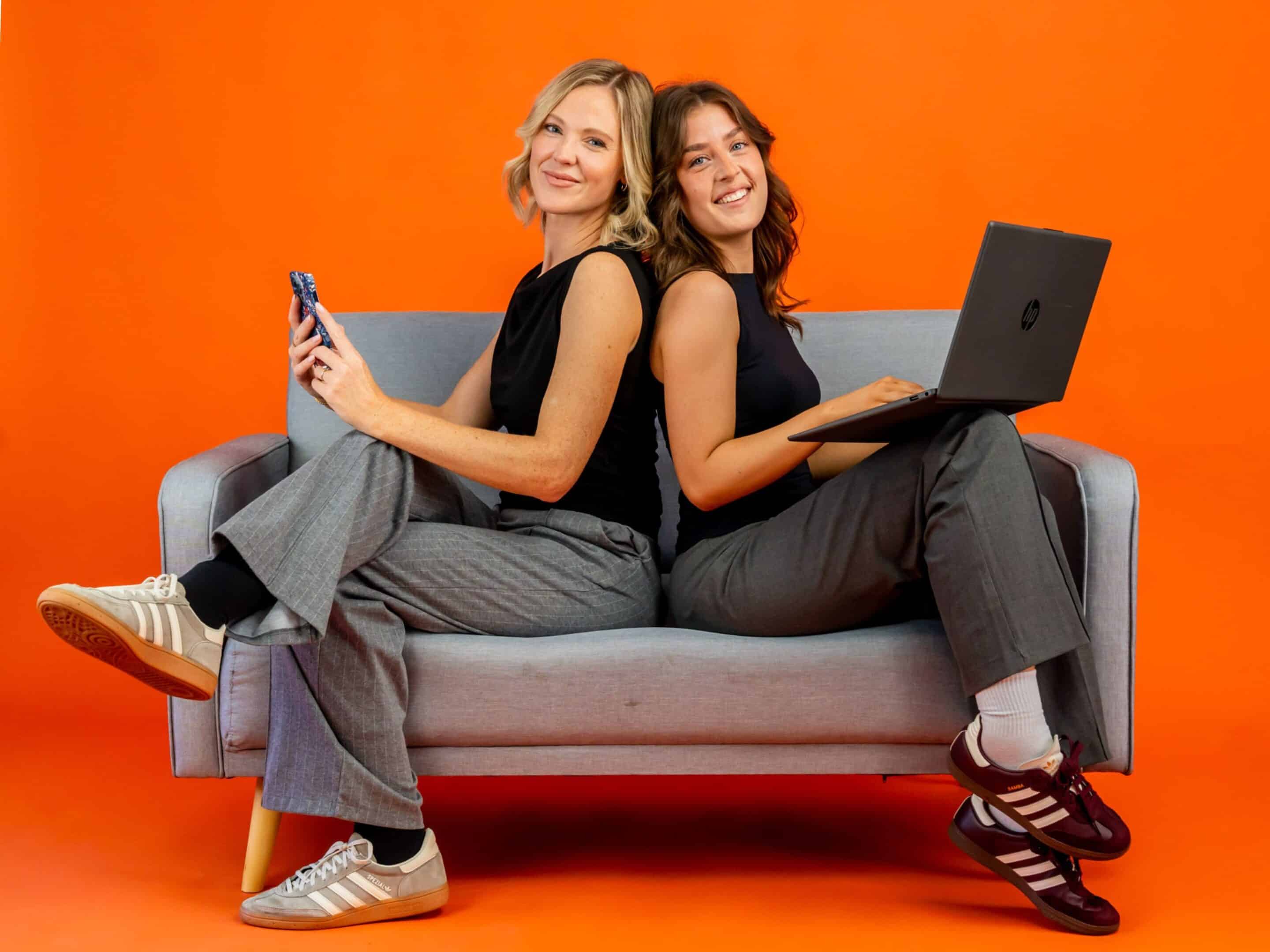 Prime mix branded photos 2 people sitting on sofa with orange backdrop
